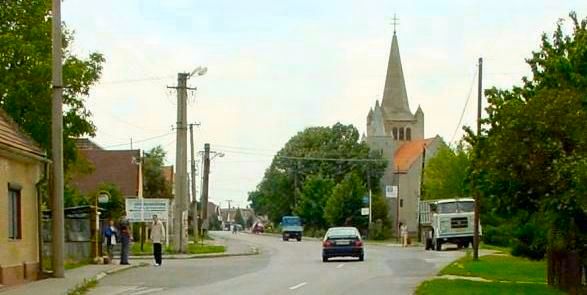 Hlavná cesta v Moste pri Bratislave pri príjazde od Bratislavy. Pred kostolom odbočte vpravo a hneď doľava, sme z druhej strany kostola než je hlavná cesta.